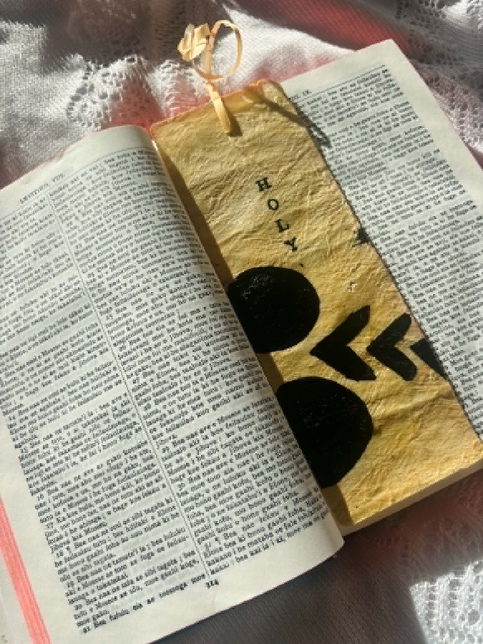 Gold fabric bookmark with large black heart-like symbols and cord tie