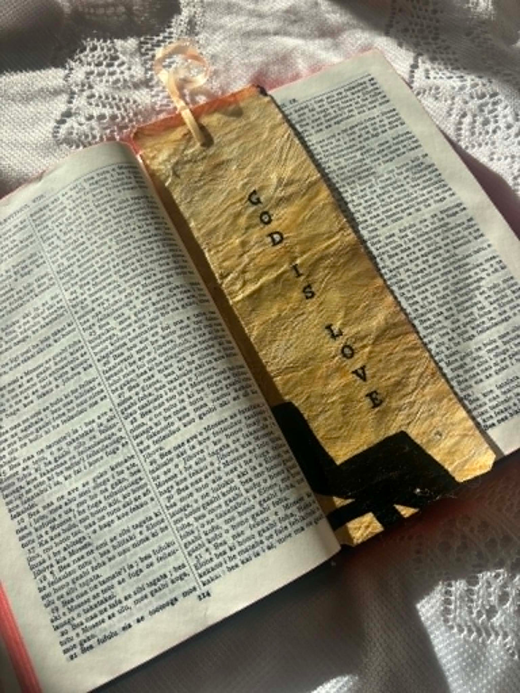 Gold bookmark with black letter wordmark and tassel, set against open book pages