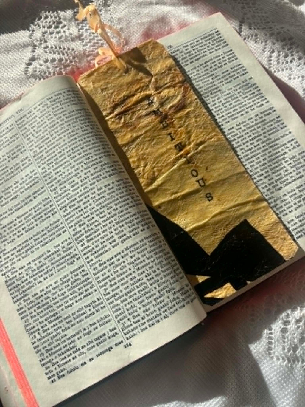 Gold fabric bookmark with black cross motif and small cord loop on book