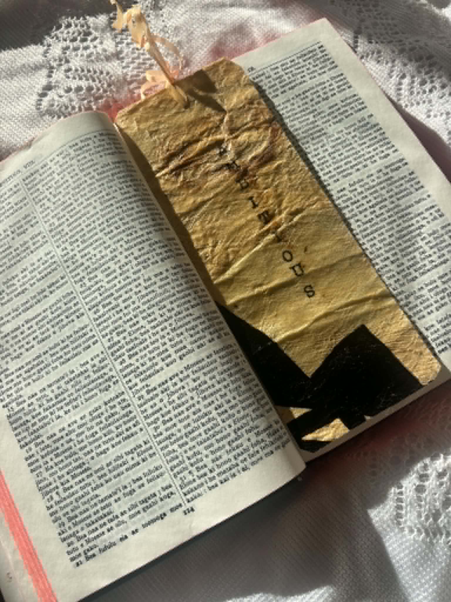 Gold fabric bookmark with black cross motif and small cord loop on book