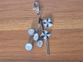 Silver keychain with three white discs, star charms, and key