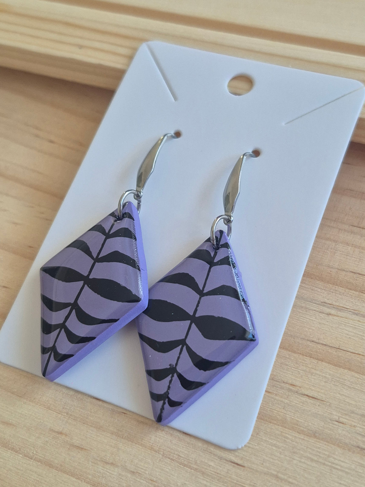 Lavender patterned triangular drop earrings on silver-tone hooks, close-up view