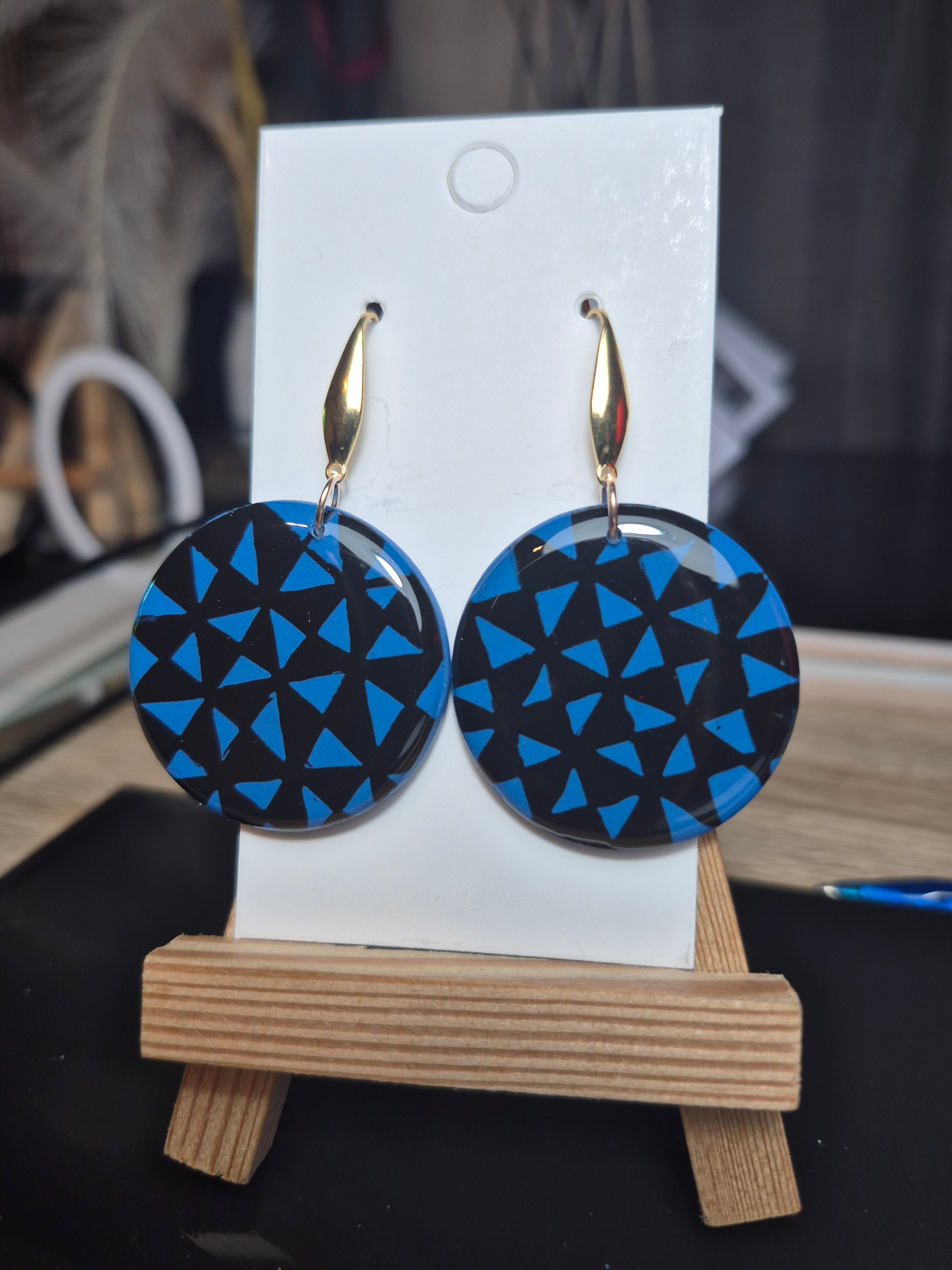 Manulua circle earrings, blue geometric discs with gold-tone hooks on display card.