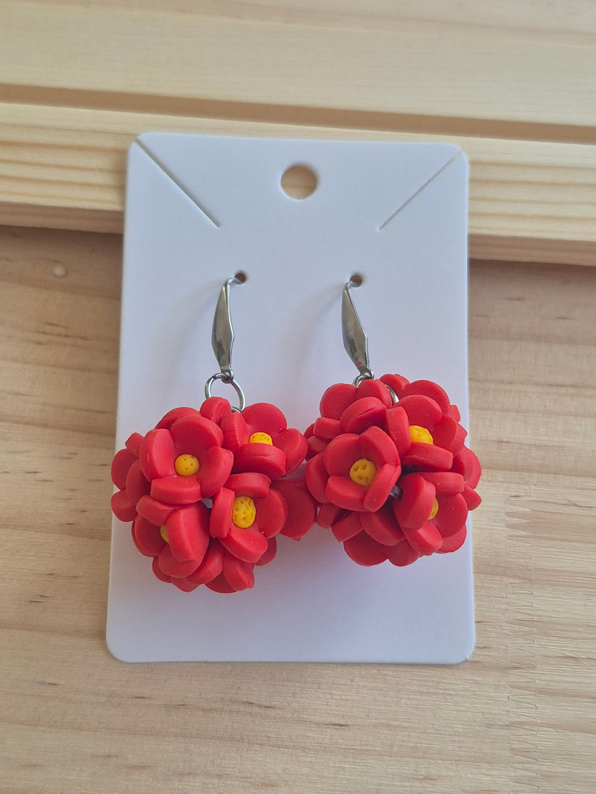 Red flower dangle earrings with small yellow centers and silver hooks